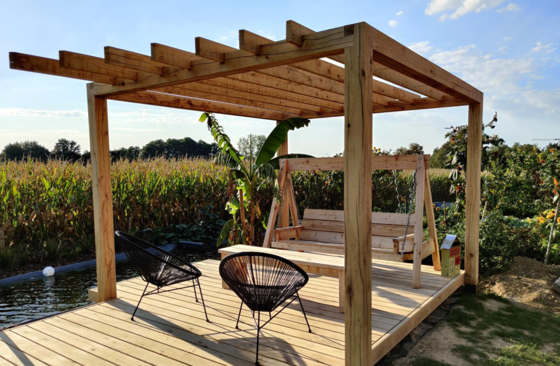 Elegante houten pergola met terras en geïntegreerde schommel in natuurlijke omgeving